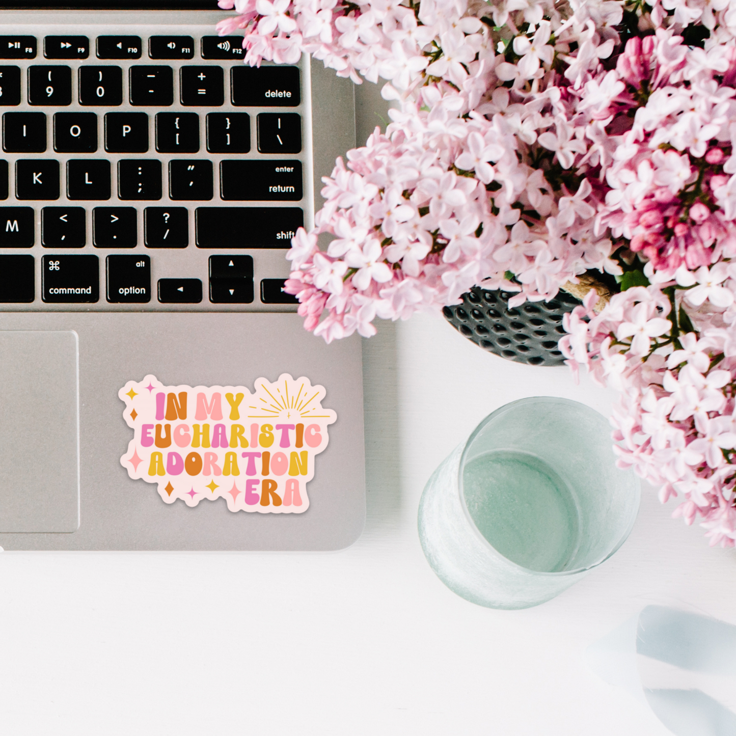 a laptop computer sitting on top of a desk next to pink flowers