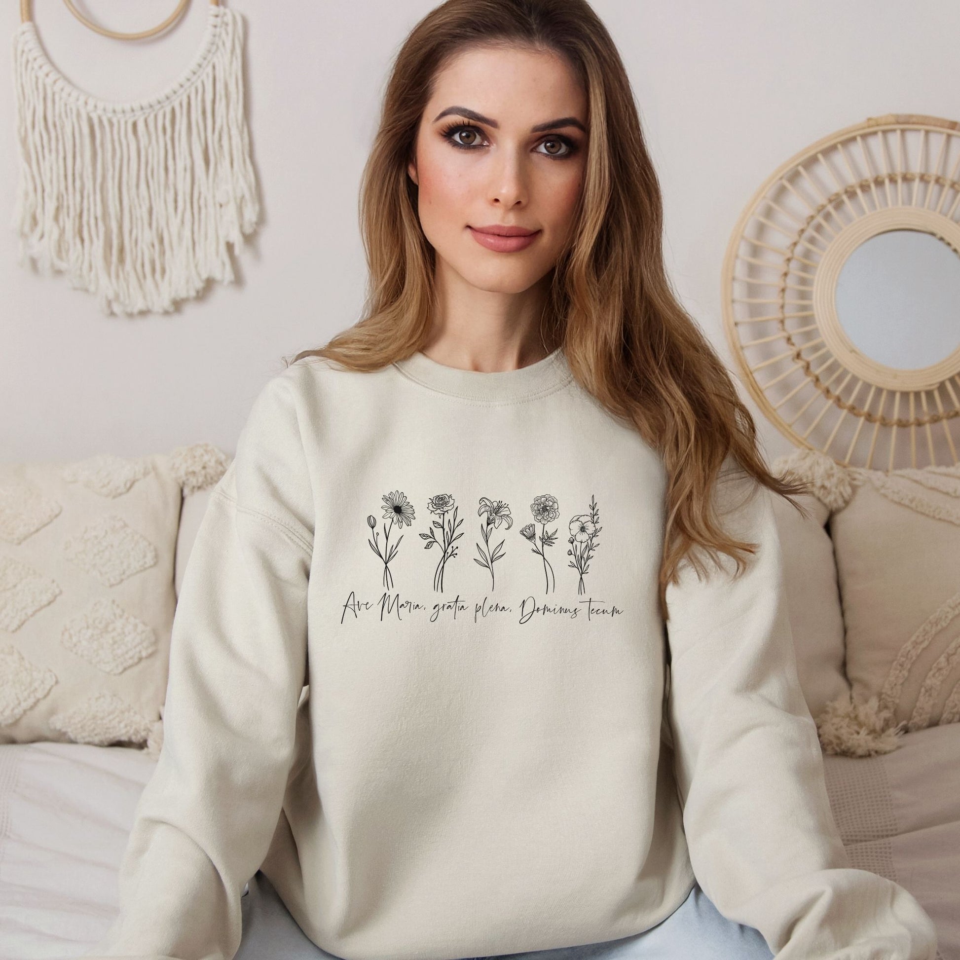 a woman sitting on a bed wearing a sweater with flowers on it